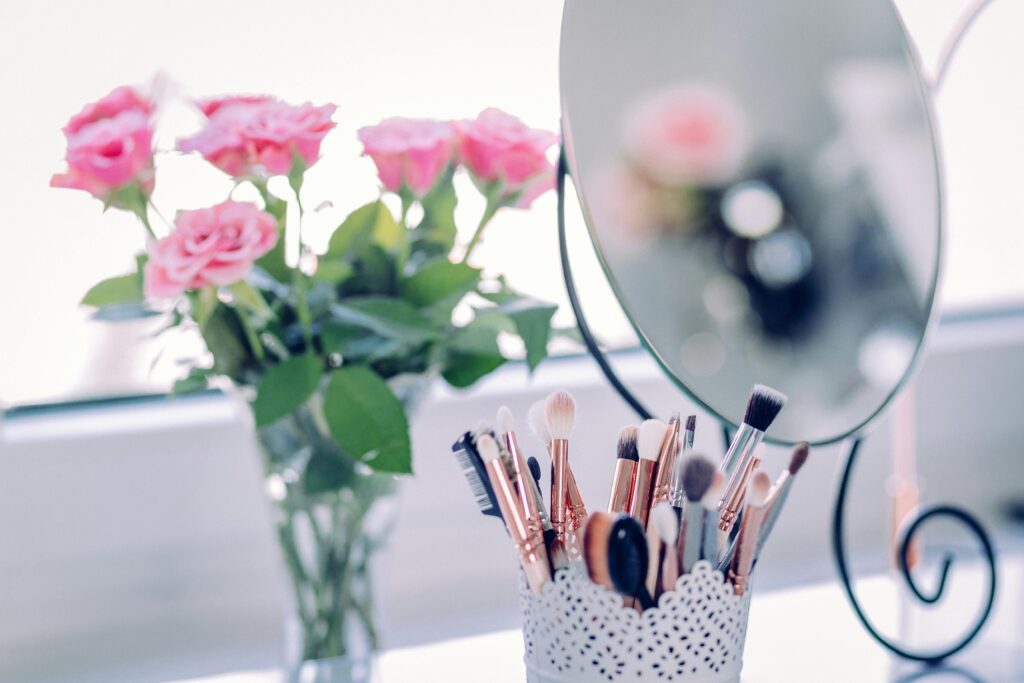 A delicate arrangement of roses with makeup brushes and a mirror, perfect for beauty and decor themes.